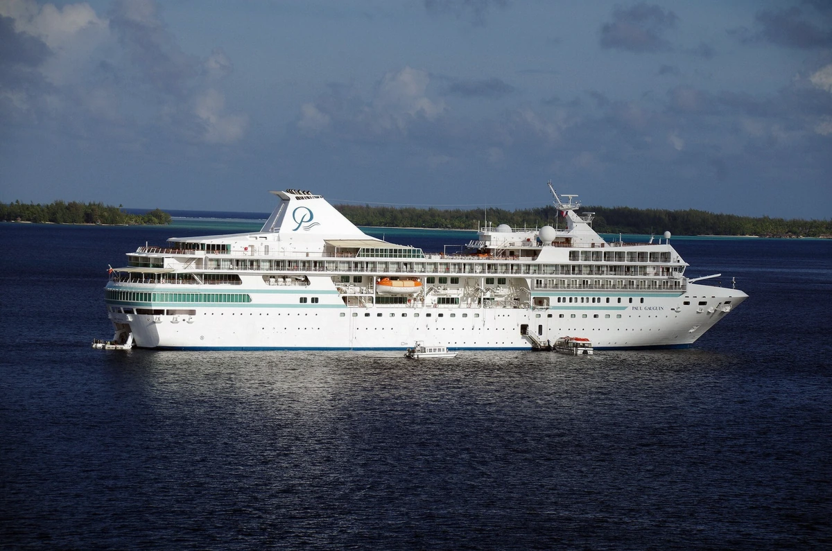 Cruise ship anchored in the Bora Bora lagoon off Vaitape with tour boats running past, French Polynesia